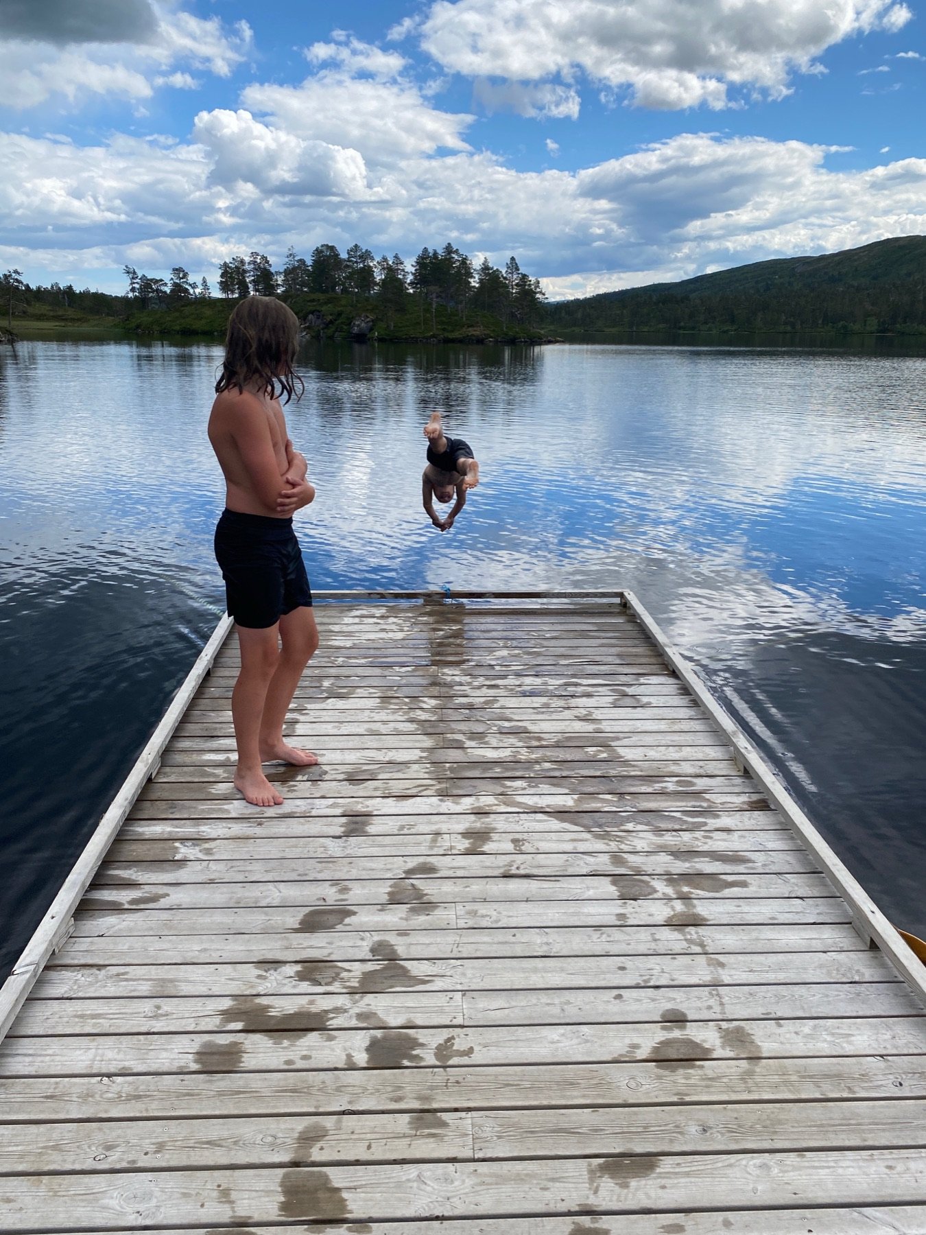 Barn står på brygga og ser ut over Langvatnet en sommerdag