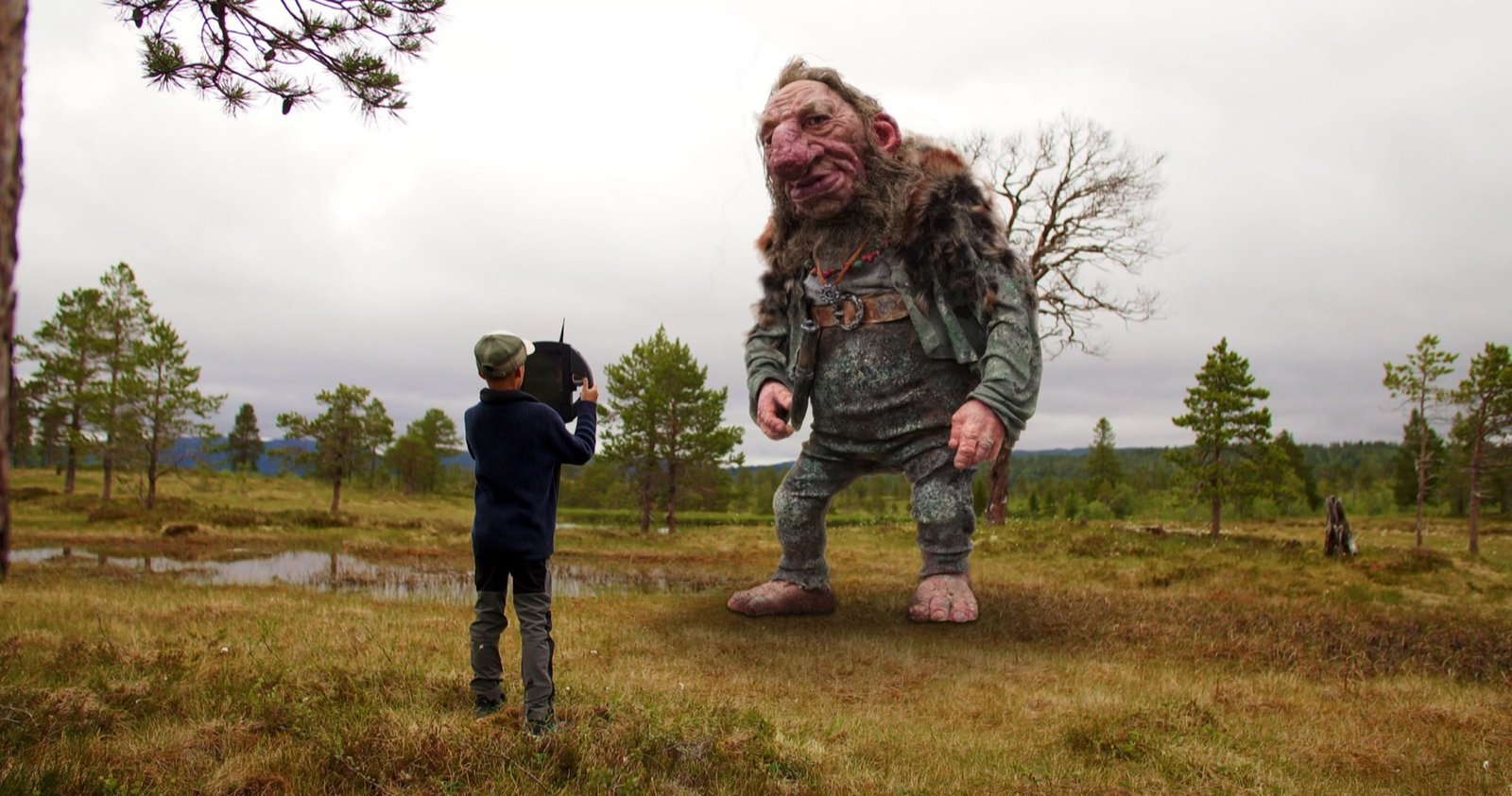 Gutt med trolldetektor står ansikt til ansikt med et troll på myra