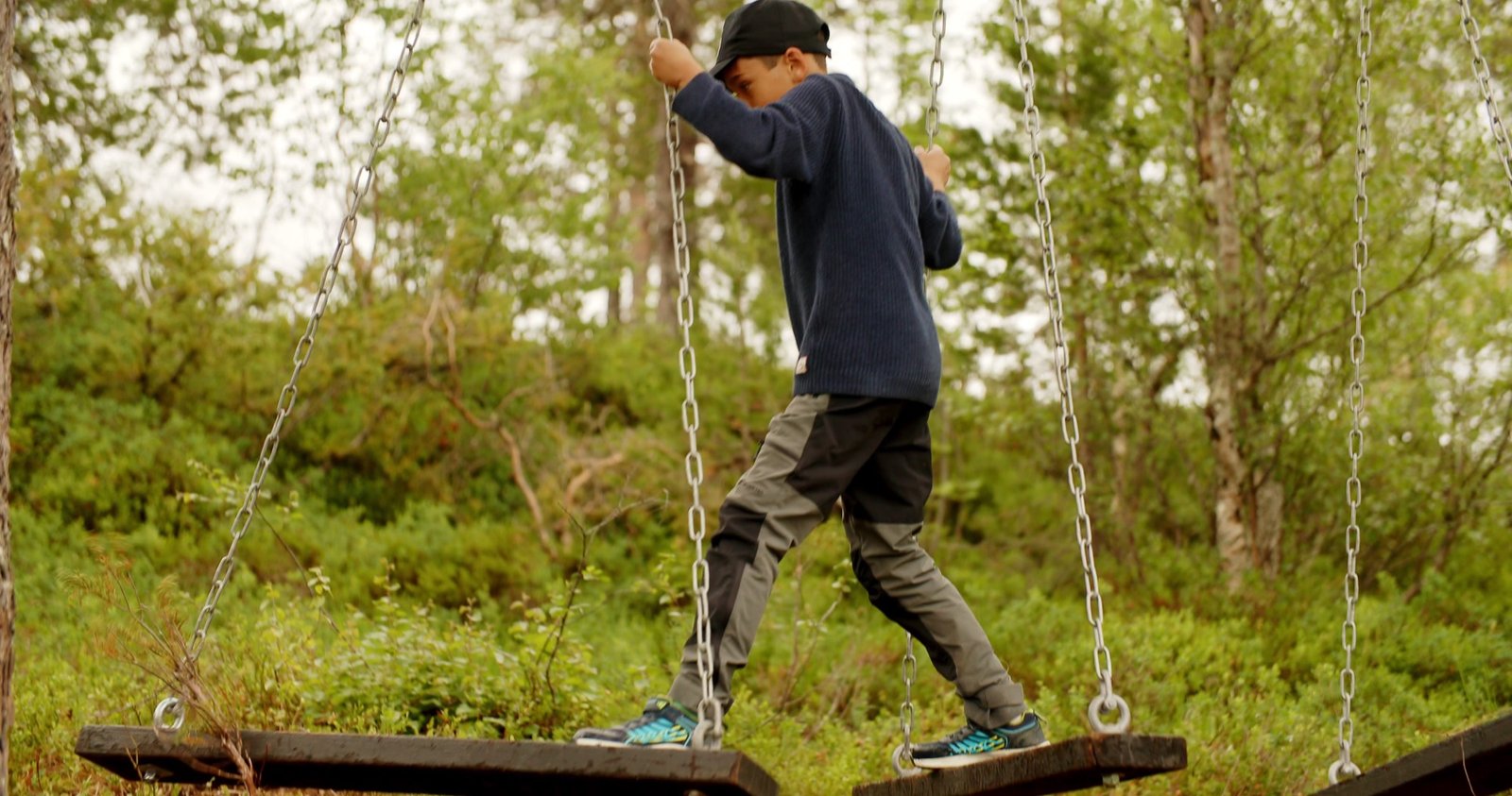 Gutt som balanserer på en tausti i skogen